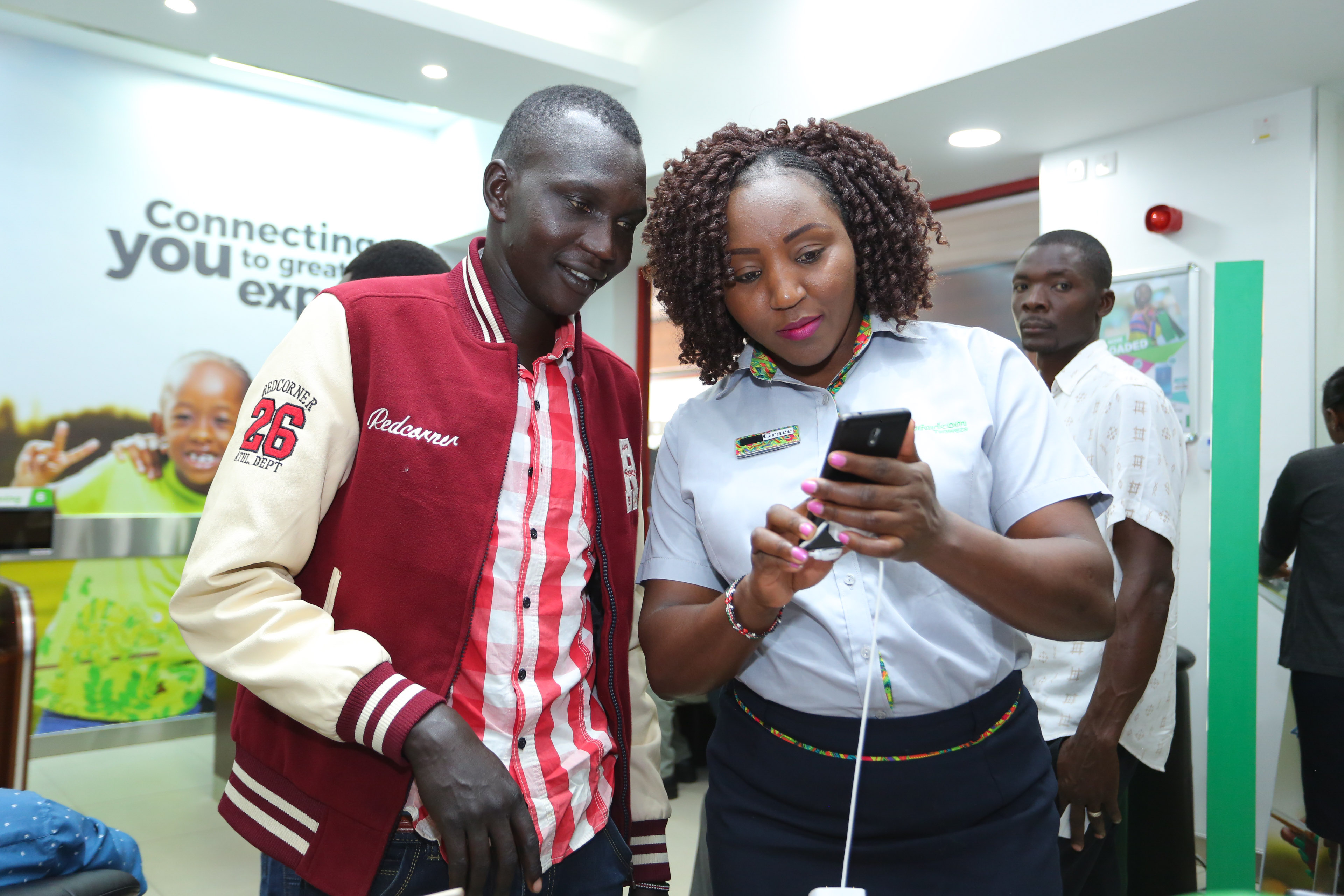 Safaricom Customer experience executive, Grace Wanjiru (right) explains to Jackson Sorkwony (customer) features of some new devices being sold at the newly opened Safaricom Westside Shop in Nakuru - Bizna