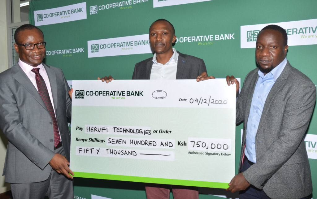 Vincent Marangu - Director, Co-operatives Banking at Co-op Bank hands the Sh 750,000 prize money dummy cheque to Herufi Technologies duo of Projects Manager Dan Onyango and Technical Director James Ngugi, being one of the winners of Akili Kali Innovators Challenge