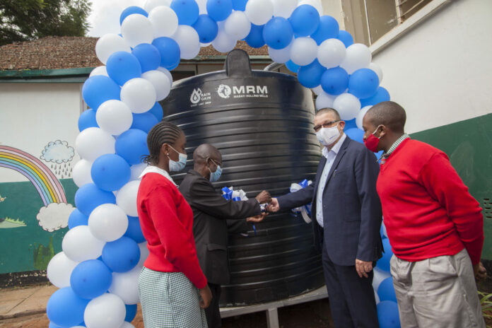 Mabati Rolling Mills CEO Andrew Heycott (2nd right) and Westlands Primary Head Teacher Fredrick Otieno (2nd left) cut a ribbon to commemorate the handover of the RainGain Water Harvesting System by MRM. Looking on are students Shannice Ongonche and Jaynichle Matwetwe - Bizna Kenya