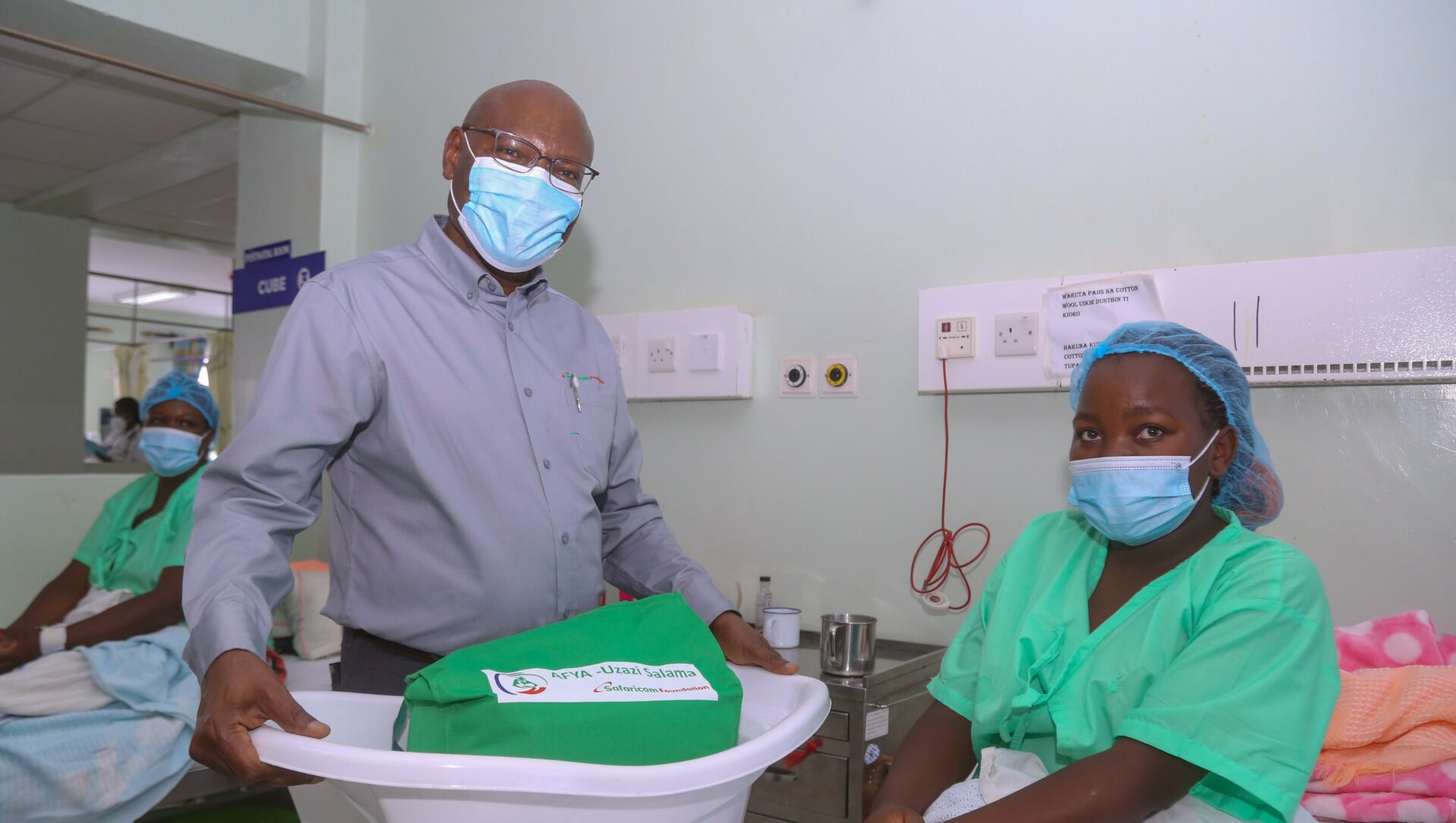 Safaricom Foundation Chairman, Joe Ogutu (standing) hands over Mama Pack to Judy Waithera, during Safaricom Foundation’s handover of a Maternal HDU and Newborn unit in KNH Othaya, Nyeri County - Bizna Kenya