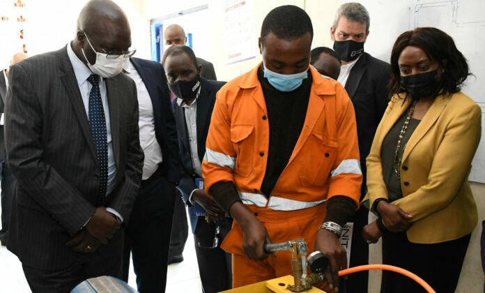 NITA automotive engineering student Salim Abani (L) demonstrates her skills to CS Labour Hon. Simon Chelugu and Plan International Country Director Kate Maina - Vorley at NITA-Athi River, Bizna Kenya