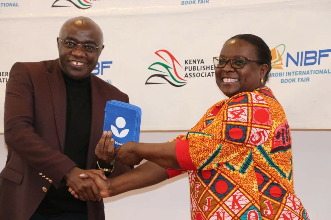Worldreader Regional Manager East Africa Joan Mwachi presents a donation of e-readers to the chairman of the Kenya publishers association Kiarie Kamau during the International Book Fair in Nairobi. The e-readers were awarded to budding writers who won in the Jomo Kenyatta literature prize and Wahome Mutahi literature - Bizna Kenya