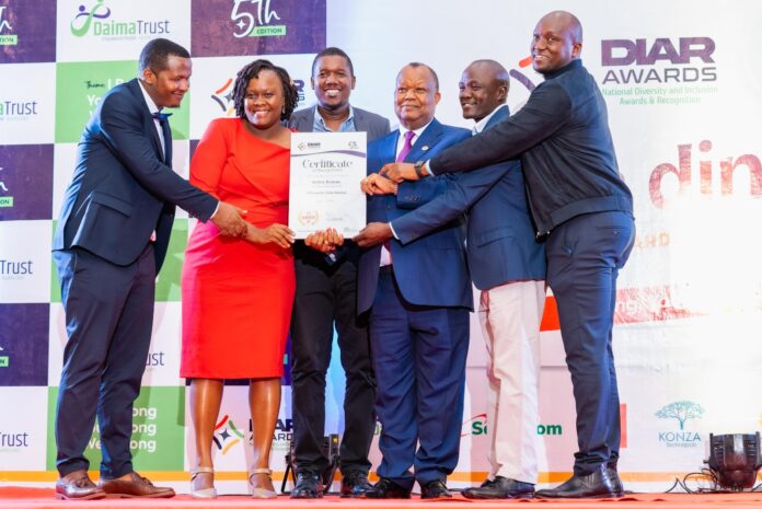 National Council for Population and Development (NCPD) Chairman Gen (Rtd) Dr. Julius Waweru Karangi presents the National Diversity and Inclusion Awards & Recognition (DIAR) second 'Most Inclusive Listed Company ' Award to Bamburi Cement PLC's HR Business Partner & Diversity, Equity and Inclusion Manager Beatrice Kirubi and staff. Bamburi Cement PLC's Country Chief Executive Officer Seddiq Hassani also notched second in the 'C-Suite Executives' Award - Bizna Kenya (Picture Courtesy)