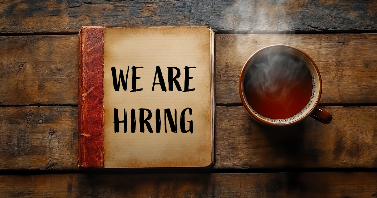We are hiring sign on a book and a cup of coffee