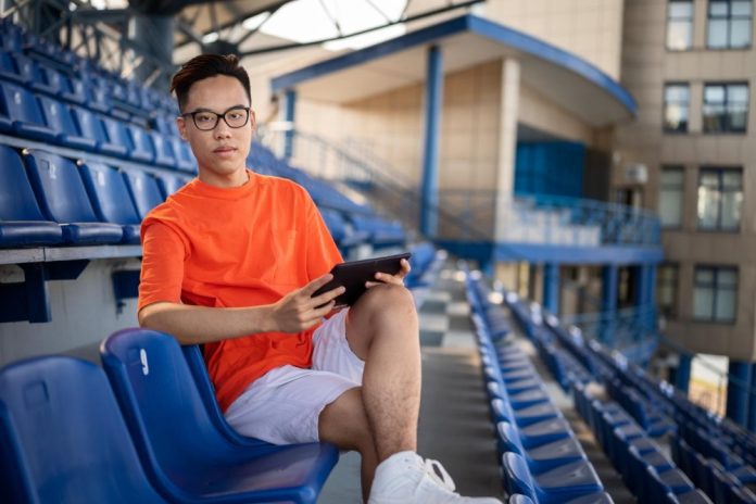 Young man using a tablet at a stadium